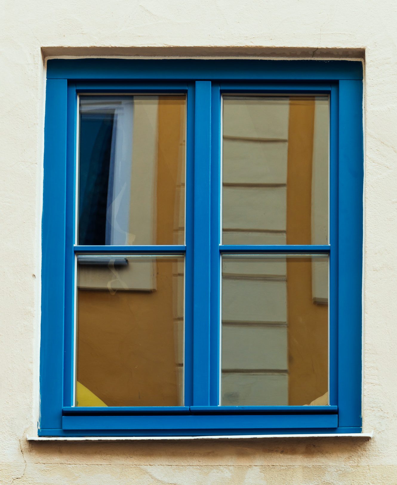 Wooden window painted in blue and building reflections on glass